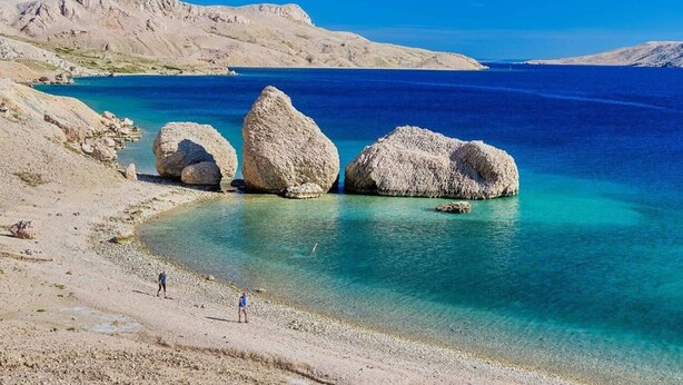 A beach with large boulders and clear blue water. - Apartments Draga (Novalja)