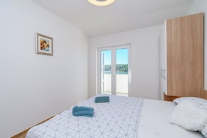 A bedroom with a bed, a wardrobe, a picture on the wall, and a view through the door. - Apartment Ren (Rab)
