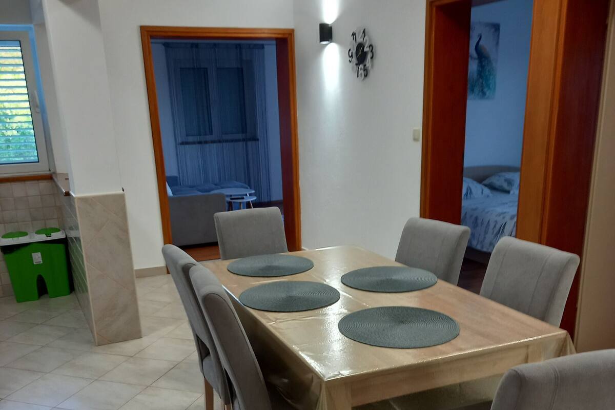 A dining area with a wooden table, grey chairs, and a clock on the wall.