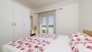 Ein Schlafzimmer mit Bett, Kleiderschrank, Schreibtisch und einem Fenster mit Vorhängen.