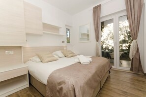 Ein Schlafzimmer mit Bett, Nachttischen, einem Fenster und Blick ins Freie.
