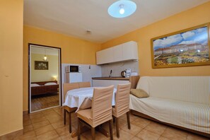 A compact living space with a dining area, kitchenette, and a sofa. - Apartments Ivan (Rab)