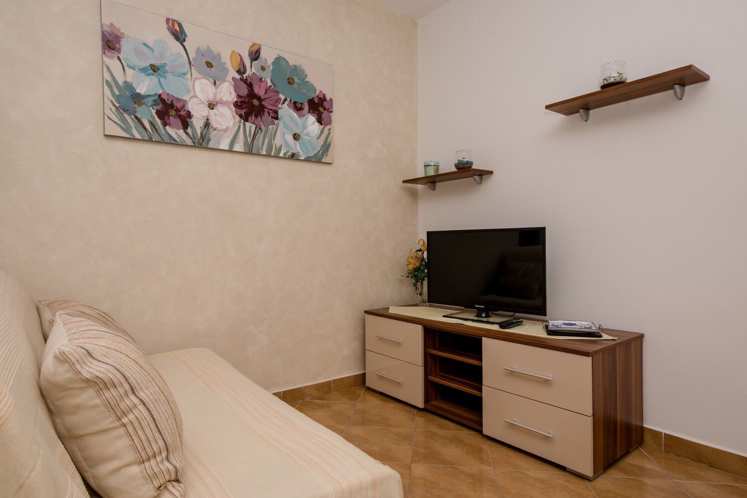 Une chambre avec un lit, un bureau avec une télévision et un tableau accroché au mur.