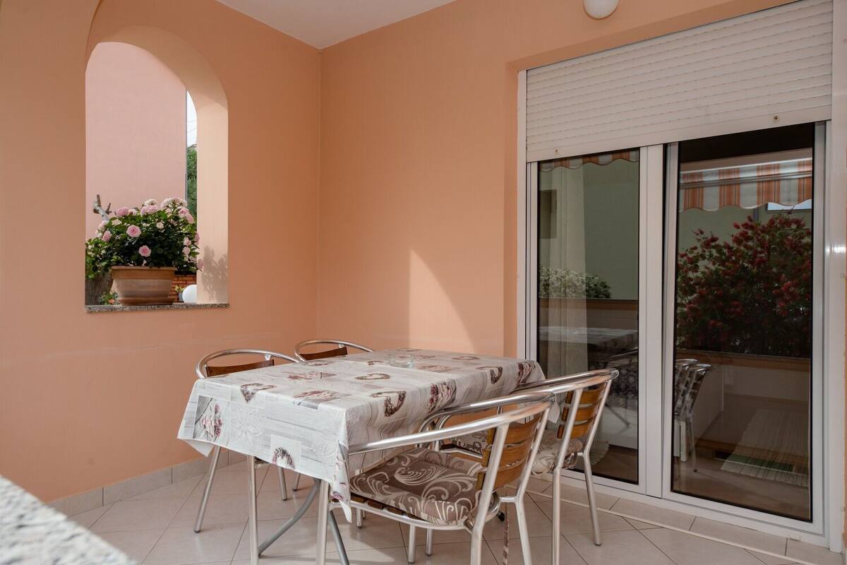 Un comedor con una mesa y sillas, una planta en maceta y un ventanal corredero que da a un espacio exterior.