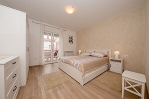 A bedroom with a bed, bedside tables, a wardrobe, a balcony, and a view of the outside. - Apartments Mar (Rab)