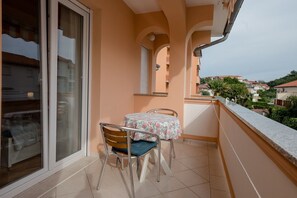 Un balcone con tavolo e sedie, una porta scorrevole in vetro e vista sul quartiere.