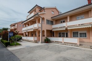A multi-story residential building with balconies and a sign indicating it is an apartment complex. - Apartments Mar (Rab)