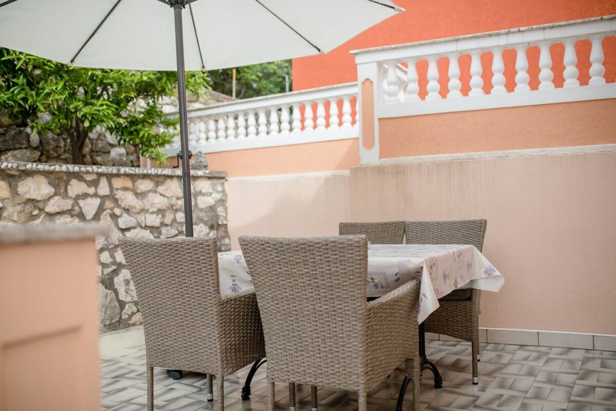 Un patio con mobiliario de mimbre y una mesa cubierta con mantel blanco.