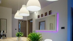 A modern interior with a wooden dining table, hanging pendant lights, and a neon sign on the wall. - Apartments Spomenka (Rab)