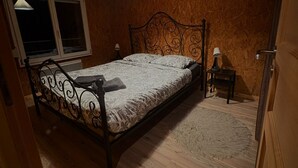 A bedroom with a wooden ceiling, a metal bed frame, a window, and a nightstand with a lamp. - Apartment for up to 6 people in Réguisheim (Réguisheim)