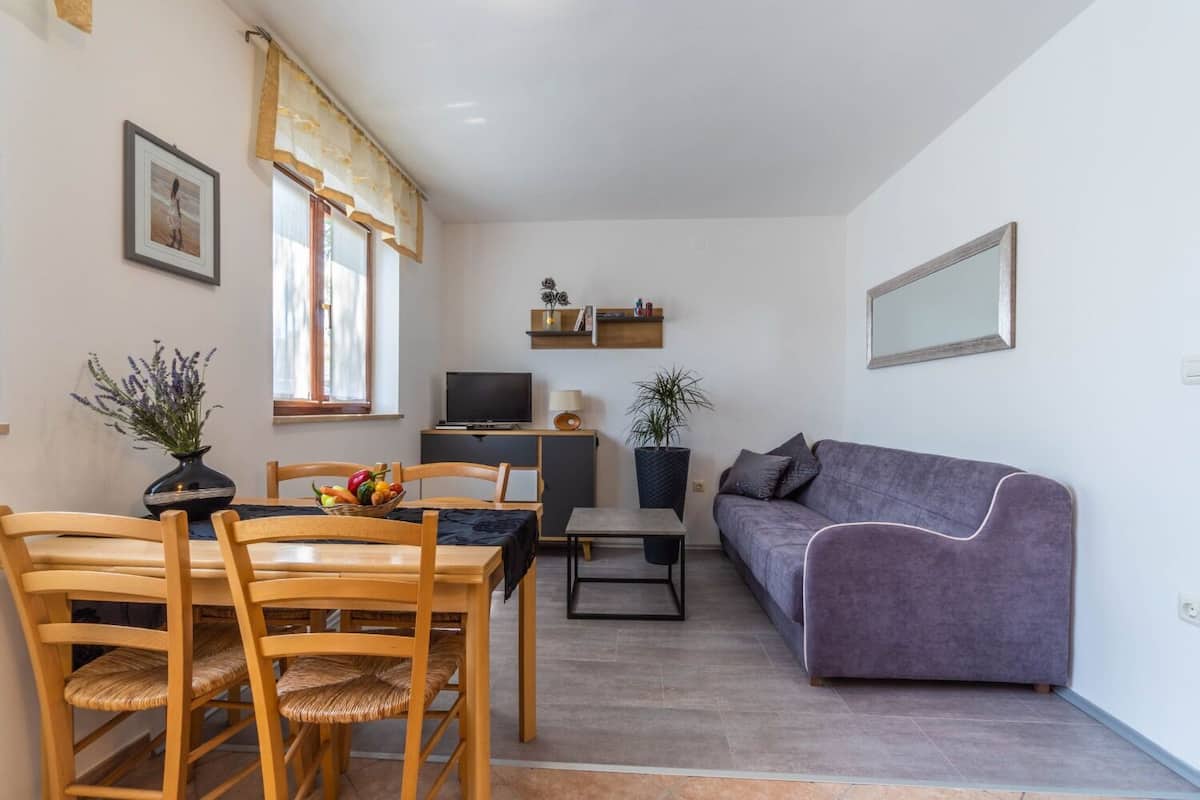 Un espacio habitable compacto con comedor, sofá, televisor y una mesita.