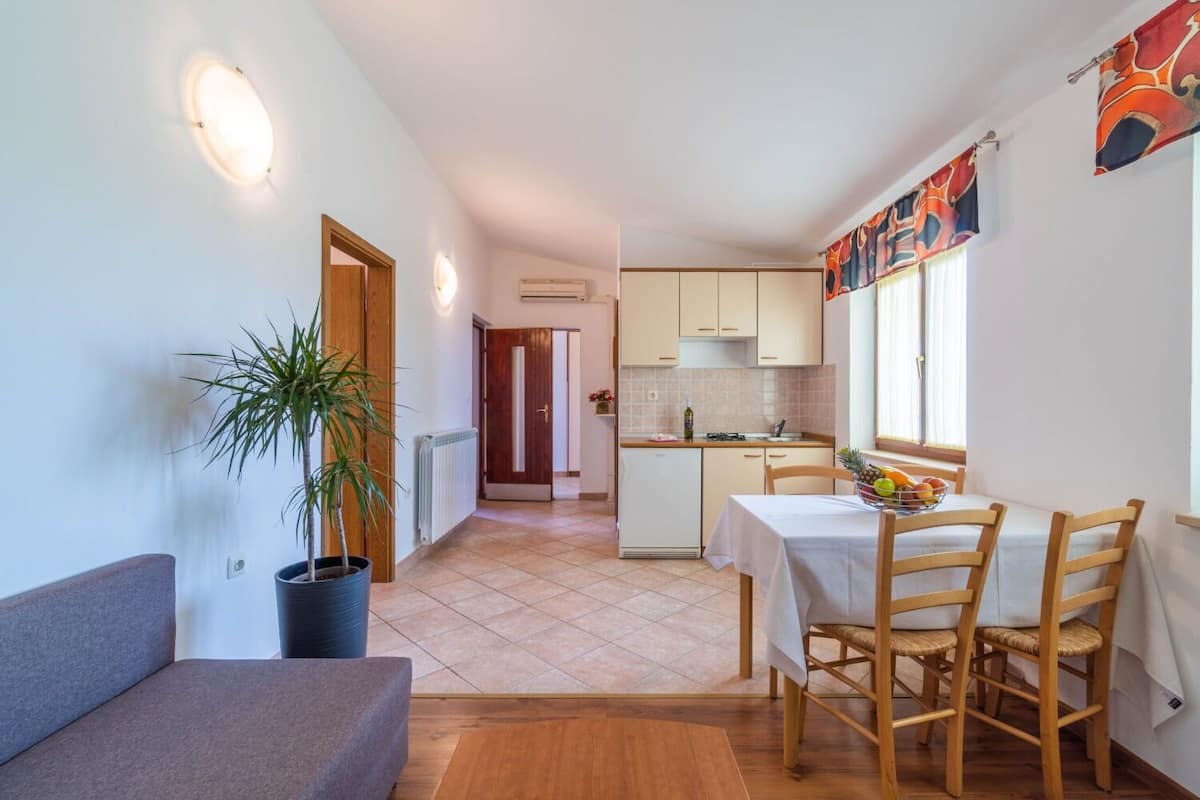 Un espacio habitable compacto con kitchenette, una zona de comedor con mesa y sillas, y un sofá.