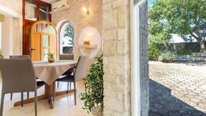 Un comedor con una mesa, sillas, una planta en maceta y una pared de piedra.
