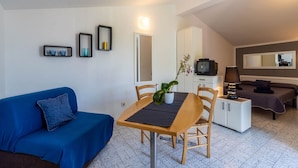 A compact living space with a dining area, a sofa, a TV, and a bed. - Apartments Perci (Marcana)