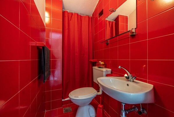 A bathroom with red tiles, a white toilet, and a white sink. - Apartments Perci (Marcana)