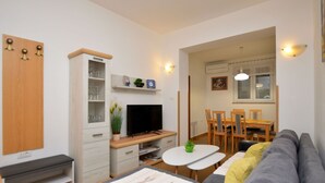 A modern living room with a sofa, TV, dining table, and chairs. - Apartment Gianfranko (Opatija)