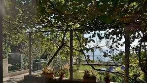 A garden area with potted plants, a swing, and a view of the sea. - Apartment Gianfranko (Opatija)