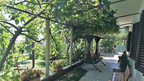 A covered outdoor area with a swing chair, potted plants, and a bench. - Apartment Gianfranko (Opatija)