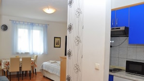 A compact living space with a dining area, a bed, a kitchenette, and a bathroom. - Apartments Ivi (Makarska)