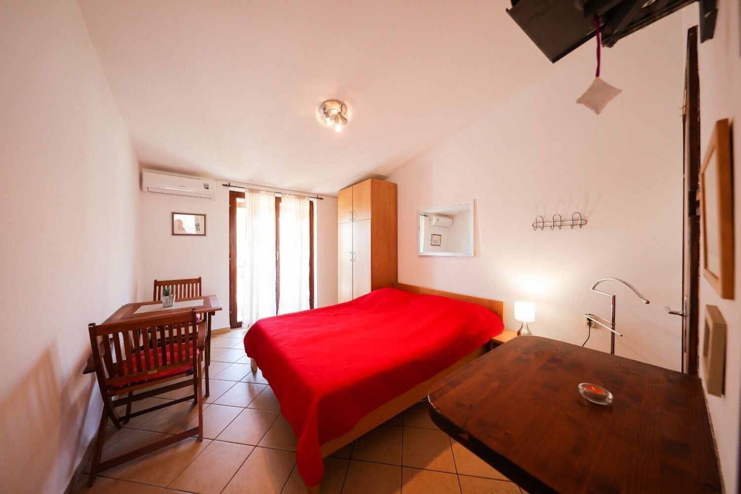 Um quarto com uma cama, uma mesa de madeira, uma escrivaninha e uma cadeira.