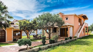 Eine Villa im mediterranen Stil mit Terrasse, Sitzgelegenheiten im Freien und einer Treppe zum Obergeschoss.