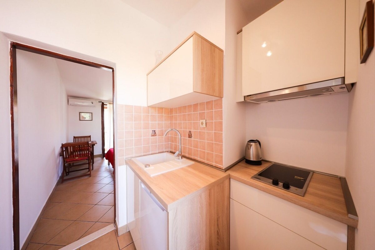 A compact kitchen with a sink, a kettle, and a stove.