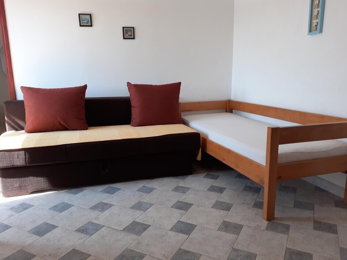 Una habitación con cama, un banco y una pequeña mesa.