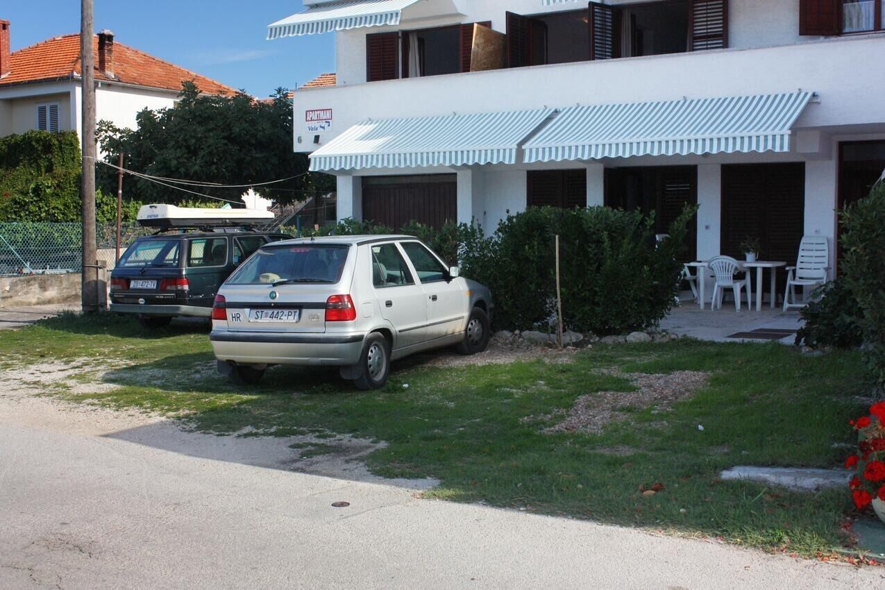 A white building with a balcony and a sign that reads "APARTMANTI".
