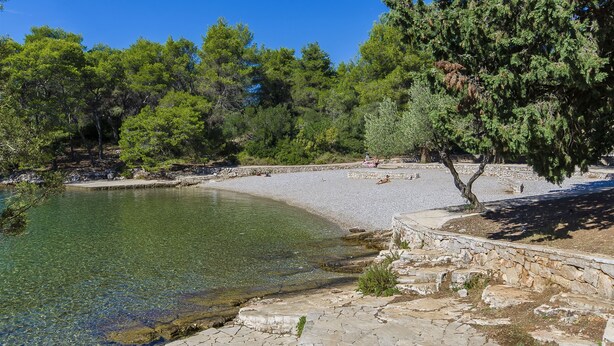 Egy tiszta vizű strand, ahol köves lépcsők és fák is találhatók.