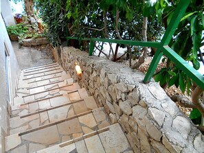 A stone staircase with a green railing, leading to a covered area with plants. - Apartments Naki (Split)
