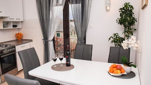 A modern kitchen with a dining table set for two, featuring a bottle of red wine and glasses. - Apartment Vrilo (Postira)