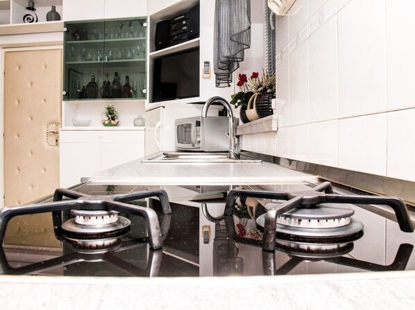 A kitchen with a gas stove, a microwave, and a sink. - Apartment Vrilo (Postira)