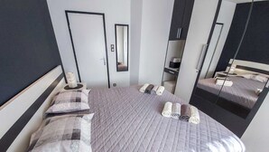 A modern bedroom with a large bed, a bedside table, a mirror, and a wardrobe. - Apartment Vrilo (Postira)