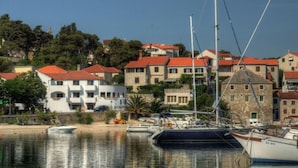 A marina with boats docked, surrounded by buildings with red roofs and stone facades. - Apartment Vrilo (Postira)