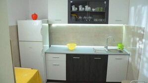 A compact kitchen with white cabinets, a grey countertop, a sink, and a small refrigerator. - House Mare (Postira)