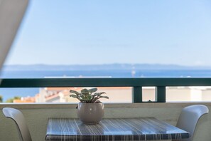 A table with a potted plant, a view of the sea, and a balcony railing. - Apartments Gianni (Makarska)