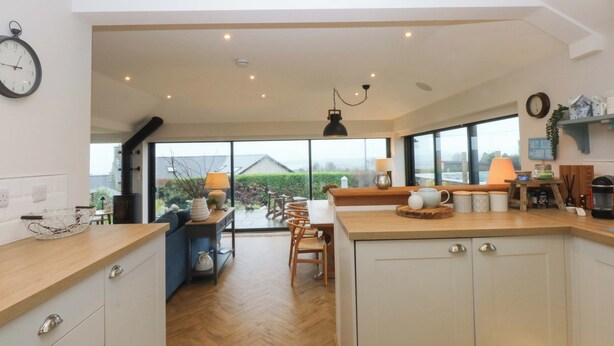 Une cuisine moderne dotée d’un grand îlot central, de meubles en bois et offrant une vue sur l’extérieur.
