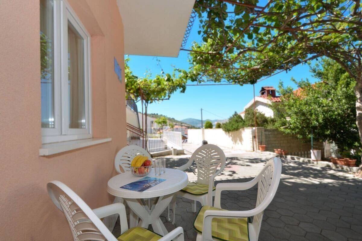 Une terrasse avec une table et des chaises, une fenêtre et une vue sur la rue et les bâtiments.