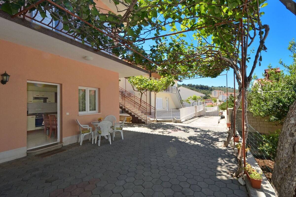 A covered outdoor area with a hexagonal tiled floor, a staircase, and a small seating area with chairs.