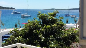 A marina with boats, a clear blue sky, and lush greenery in the foreground. - Apartments Mateo (Primosten)