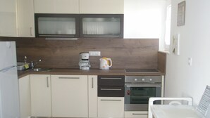 A compact kitchen with a microwave, coffee maker, and oven. - Apartments Mateo (Primosten)