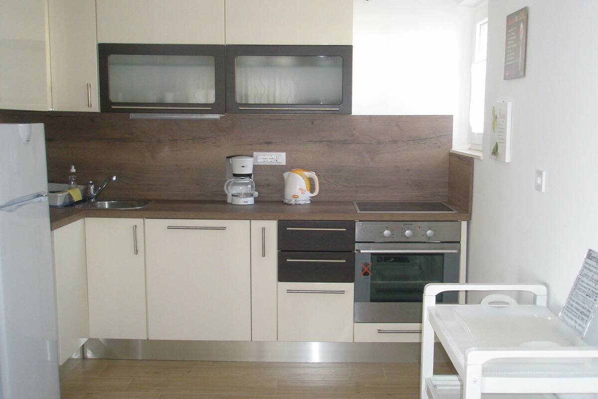 A compact kitchen with a microwave, coffee maker, and oven.