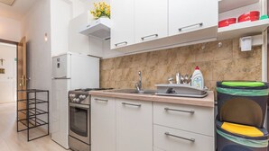 A modern kitchen with white cabinets, a stainless steel stove, and a sink. - Apartment Neva (Novigrad)