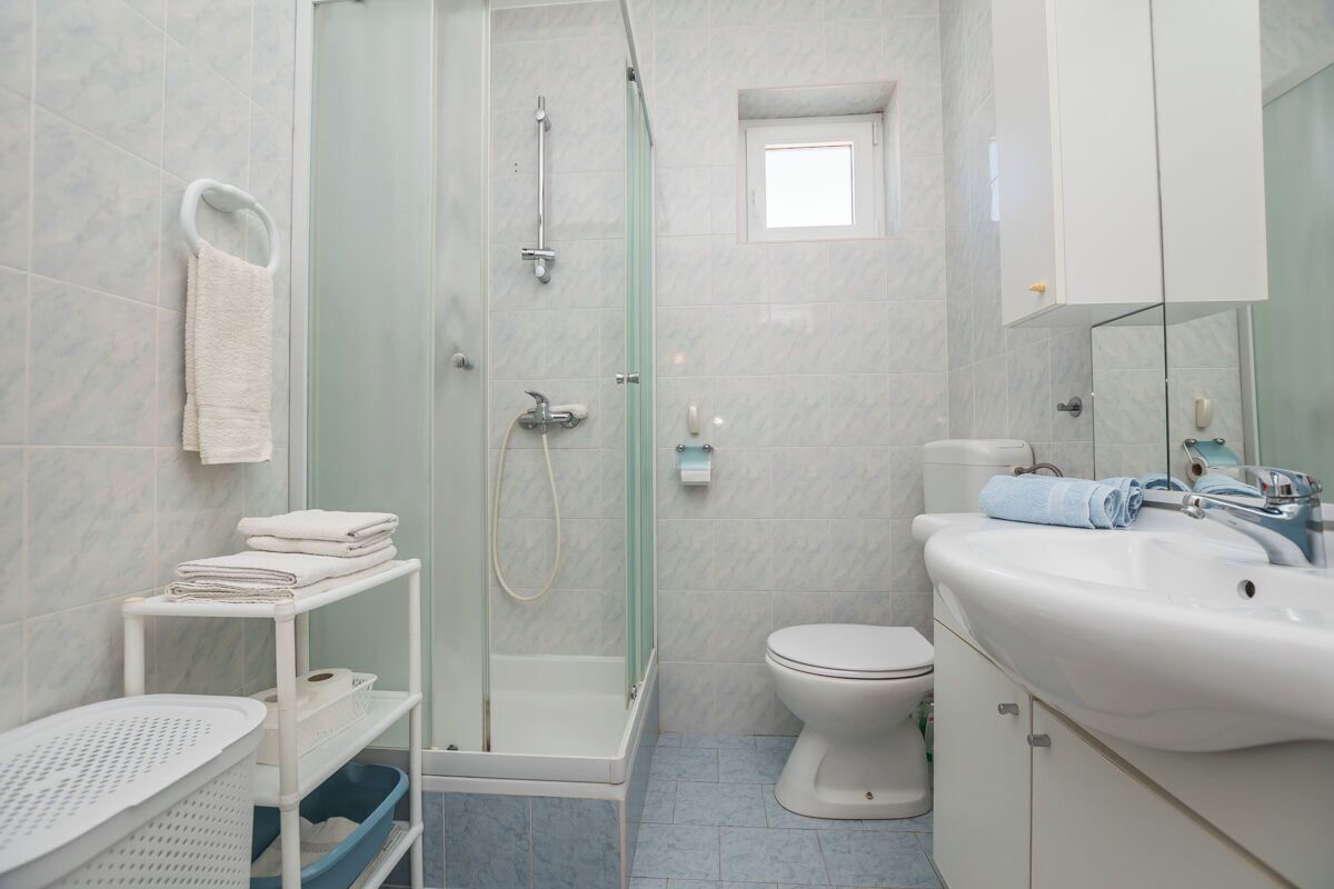 Een moderne badkamer met een douchecabine van glas, een wit toilet en een wastafel met spiegel.