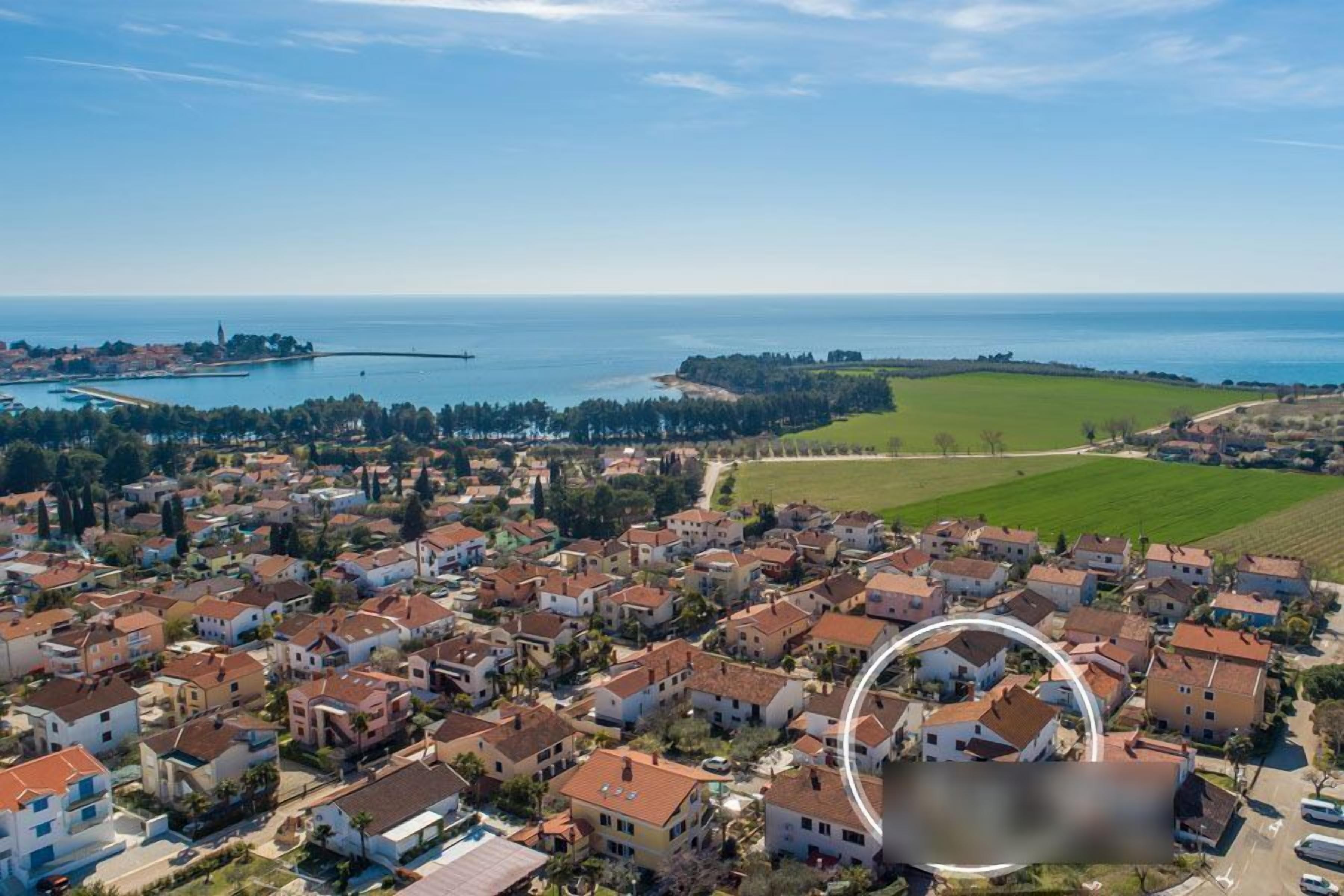 An aerial view of a coastal residential area with houses, a marina, and a lighthouse.