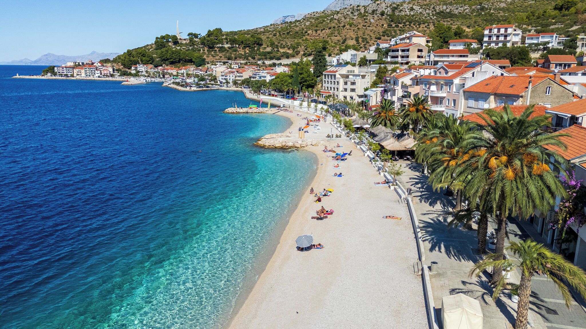 A coastal town with a beach, buildings, and clear blue sea.