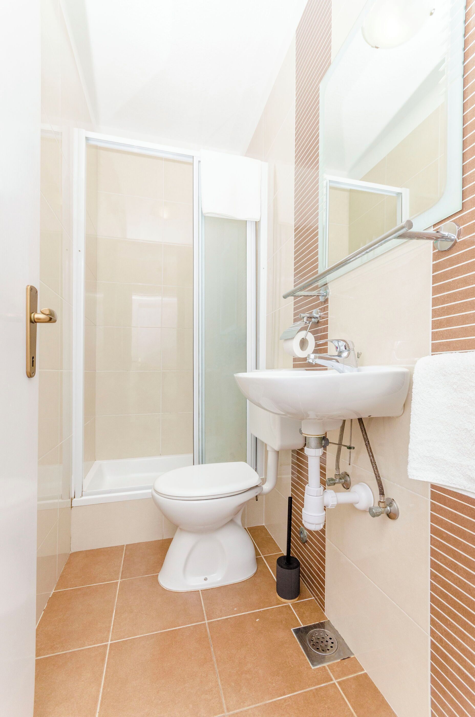 A bathroom with a toilet, sink, and glass shower enclosure.