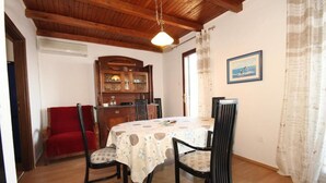 A dining area with a wooden ceiling, a table with a patterned tablecloth, and chairs. - Apartment Iva (Konavle)