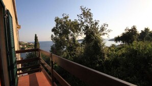 A balcony with a view of a body of water and surrounding greenery. - Apartment Iva (Konavle)