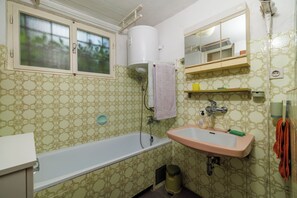 Ett badrum med badkar, handfat och ett fönster med frostat glas.